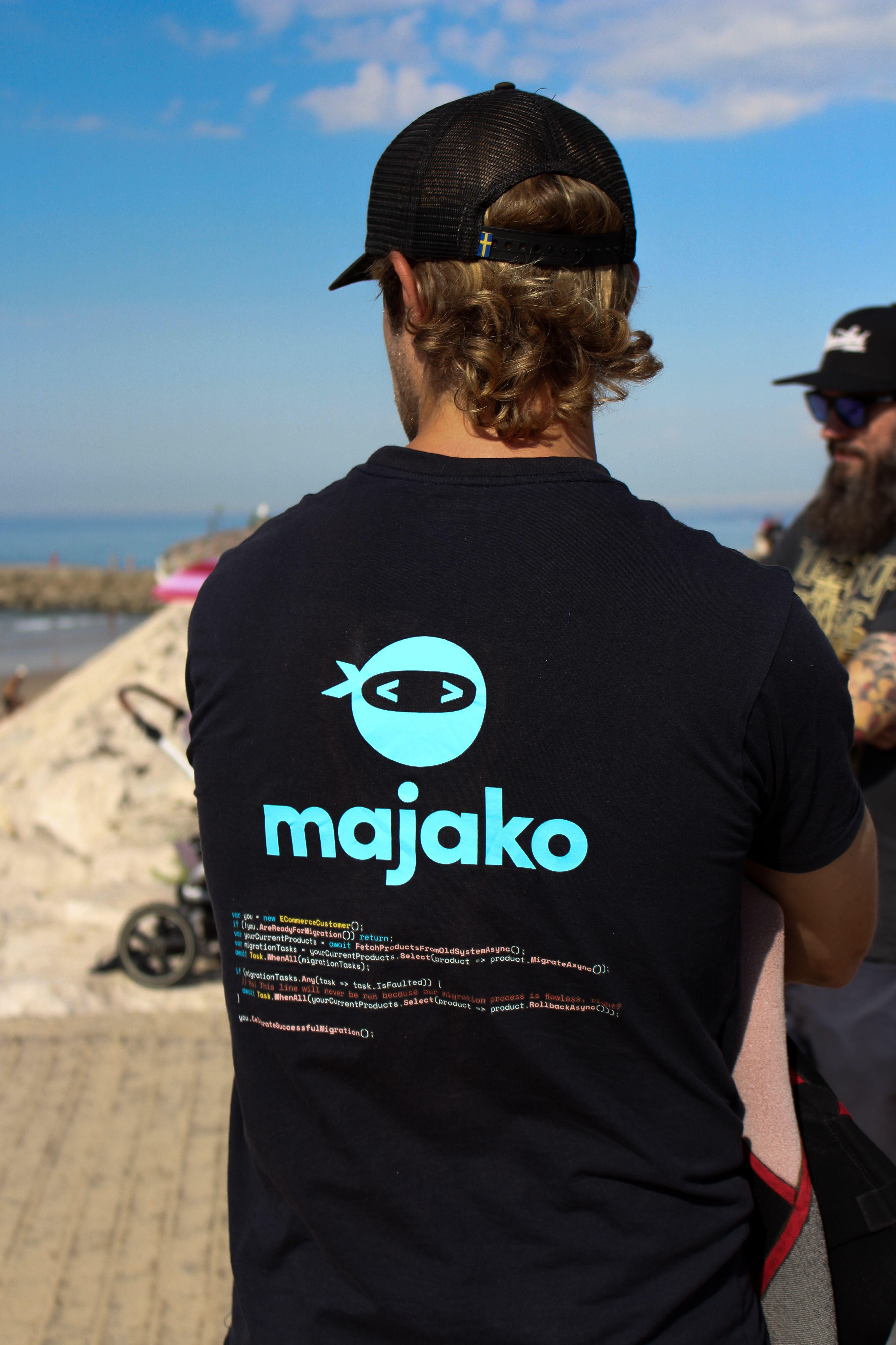 Man i svart t-shirt, keps och lockigt hår står med ryggen vänd mot kameran och tittar ut över havet.